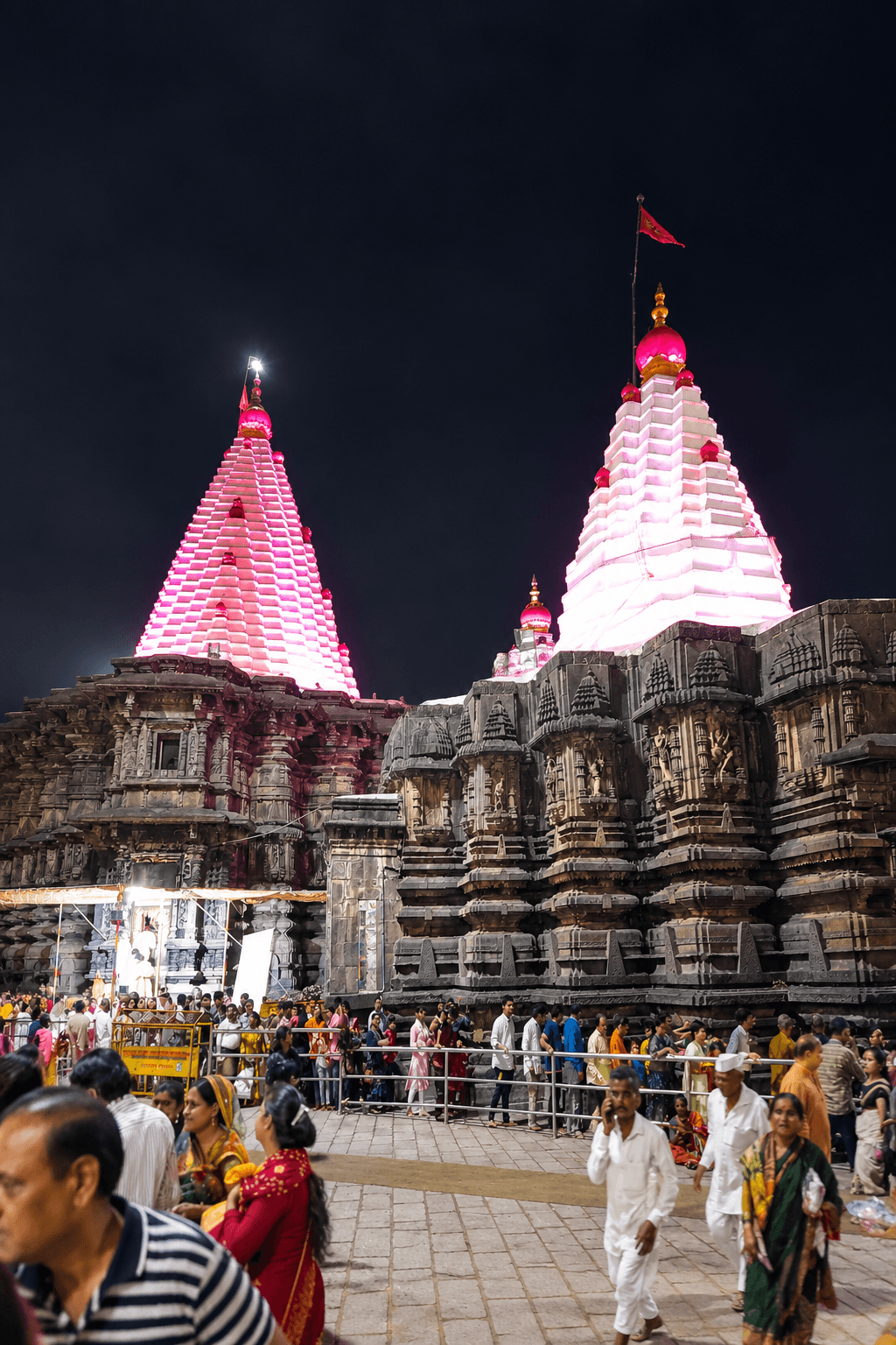 Devotees queuing in front of the illuminated shikhars of the Mahalaxmi Temple at night